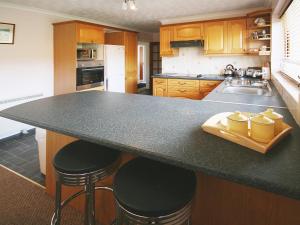 a kitchen with a black counter top and bar stools at Kildonan in Laide