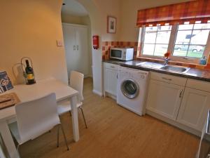 a kitchen with a washing machine and a table with chairs at Cloverfield in Bamburgh
