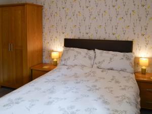 a bedroom with a bed with two night stands and two lamps at Cloverfield in Bamburgh +6 photos