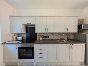 a white kitchen with white cabinets and a sink at An Mor Haven in Coverack