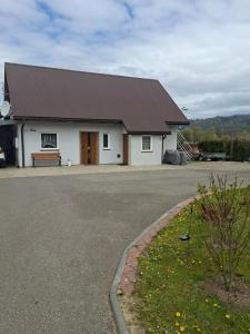 a white building with a brown roof on a street at Dom w dolinie in Zagórz