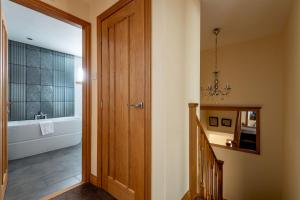 a bathroom with a bath tub and a wooden door at Dreelside - No 50 in Anstruther +25 photos