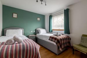a bedroom with two beds and a chair and a window at Dreelside - No 50 in Anstruther
