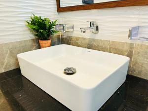 a white sink in a bathroom with a plant at Nushi Inn in Katunayaka +22 photos