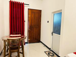 a room with a red curtain and a table and a door at Nushi Inn in Katunayaka