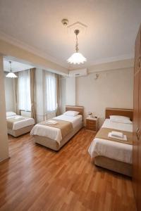 two beds in a room with wooden floors at Coskun Otel Şarköy in Şarköy +27 photos