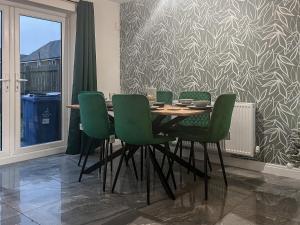 a dining room with a table and green chairs at Spring Gardens in Lower Darwen +8 photos