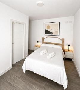 a bedroom with a white bed with two towels on it at Hospedium GL Linarejos Suites Parking Gratis in Linares