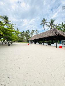 a beach with a straw hut and palm trees at Bahari Studio Beach Front Apartment. in Diani Beach