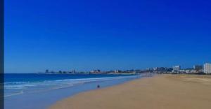 a beach with a person walking on the sand at Windermere Sands in Gqeberha
