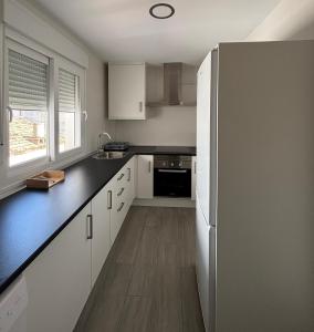 a kitchen with white cabinets and a black counter top at Hospedium GL Linarejos Suites Parking Gratis in Linares