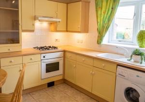 a kitchen with yellow cabinets and a stove top oven at 2 Bed Semi - Sleeps 4 - Fully Fenced Garden & Parking - Quiet Cul De Sac Location - Dog Friendly - Fast Wifi - Close to Motorway Access in Doncaster +7 photos