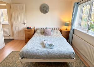 a bedroom with a bed with a blue comforter and two windows at 2 Bed Semi - Sleeps 4 - Fully Fenced Garden & Parking - Quiet Cul De Sac Location - Dog Friendly - Fast Wifi - Close to Motorway Access in Doncaster