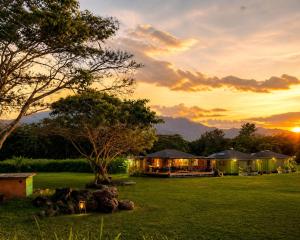 a house in a field with the sunset in the background at Pipeline Tropical Bungalow in Haleiwa