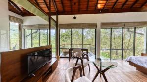 a living room with a glass table and some windows at Leaf Olu Ella in Yatiyantota