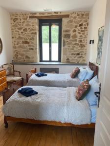 two beds in a bedroom with a stone wall at La Maison du Parc in Saint-Vite