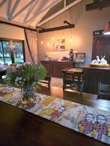 a living room with a table with a vase of flowers at 2 Owls Guesthouse in Potchefstroom