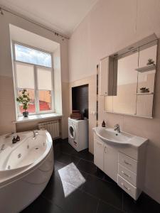 a bathroom with a tub and a sink and a washing machine at Kyiv Muse Apartment in Kyiv +15 photos