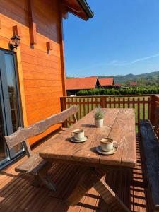 a wooden table on a deck with two cups on it at Kuća za odmor Kiara in Kolarec