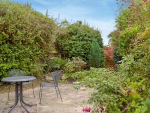 a table and two chairs in a garden at Richmond Cottage in Ashby Saint Ledgers