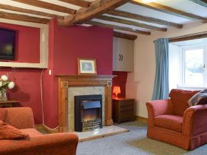 a living room with a fireplace and red walls at Richmond Cottage in Ashby Saint Ledgers