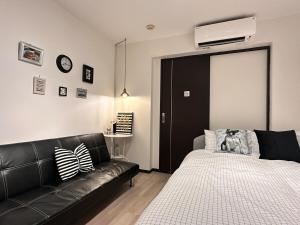 a bedroom with a black leather couch and a bed at Mori de house in kobe 302 in Kobe