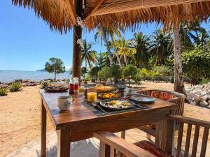 a wooden table with food on the beach at Maison le Rêve in Nosy Be