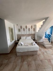 a bedroom with a white bed and a staircase at Villa Aigli in Anafi