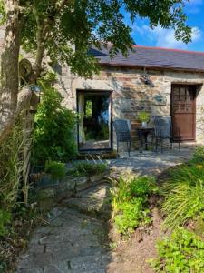a stone cottage with a table and chairs on a patio at Cobble Cottage in Cardinham