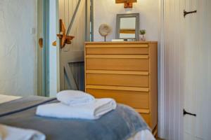 a bedroom with a dresser and towels on a bed at Cobble Cottage in Cardinham