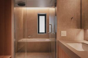 a bathroom with a glass shower and a sink at TOMI Ginza in Tokyo