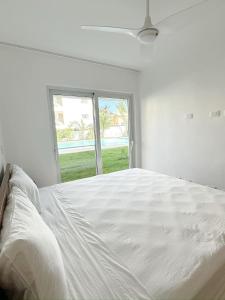 a white bedroom with a large bed with a window at Mananero Group Residence in Cabarete