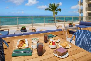 a table with breakfast food on a balcony with the ocean at OUTRIGGER Reef Waikiki Beach Resort in Honolulu