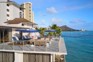 a balcony with chairs and umbrellas on the ocean at OUTRIGGER Reef Waikiki Beach Resort in Honolulu