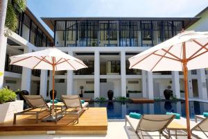 a group of chairs and umbrellas in front of a building at OUTRIGGER Surin Beach Resort in Surin Beach