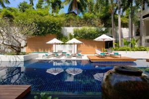 a swimming pool with lounge chairs and umbrellas at OUTRIGGER Surin Beach Resort in Surin Beach