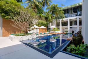 a pool at a resort with chairs and a building at OUTRIGGER Surin Beach Resort in Surin Beach