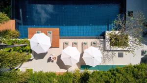 a pool with three white umbrellas on the ground at OUTRIGGER Surin Beach Resort in Surin Beach +76 photos
