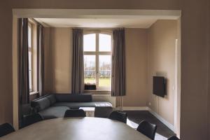 a living room with a table and a couch and a window at Portierswoning Vaeshartelt in Maastricht