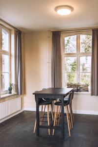 a dining room with a table and two windows at Portierswoning Vaeshartelt in Maastricht