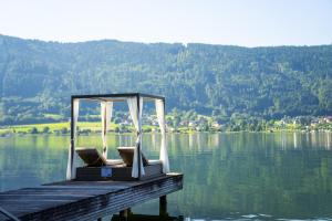 ein Steg mit ein paar Stühlen auf dem Wasser in der Unterkunft Seehotel Hoffmann in Steindorf am Ossiacher See