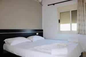 a bedroom with a bed with white sheets and a window at ANORA Mare Suites in Orikum