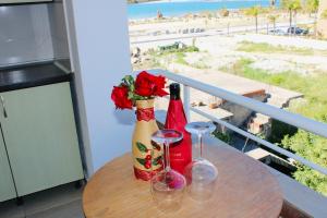 a table with two wine bottles and glasses on a balcony at ANORA Mare Suites in Orikum