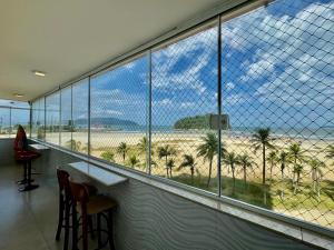 a bar with a view of the beach through windows at Verdadeiro pé na areia TOP in Santos