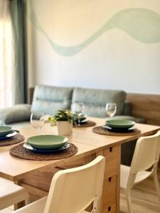 a wooden table with green plates and wine glasses at NextGen Casa Rossy in Antigua
