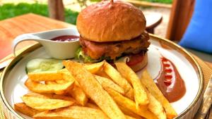 a plate with a chicken sandwich and french fries at The 5th Element Boutique Hotel in Paje