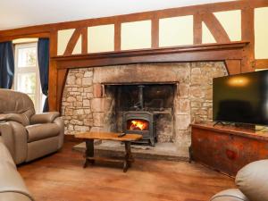 a living room with a stone fireplace with a television at Dowrich West Wing Apartment in Crediton