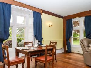 a dining room with blue curtains and a table and chairs at Dowrich West Wing Apartment in Crediton