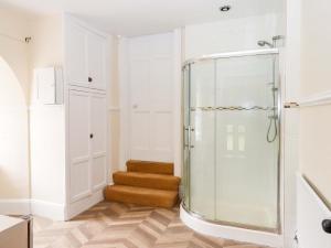 a glass shower in a bathroom with a wooden floor at Dowrich West Wing Apartment in Crediton +34 photos