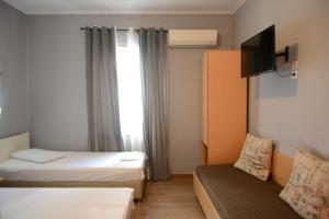 a hotel room with two beds and a couch at Electra Hotel Piraeus in Piraeus